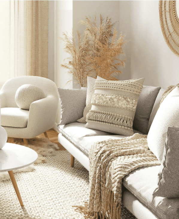 写真：白とベージュを基準とした家具が配置されている部屋のソファーとクッションが映っています